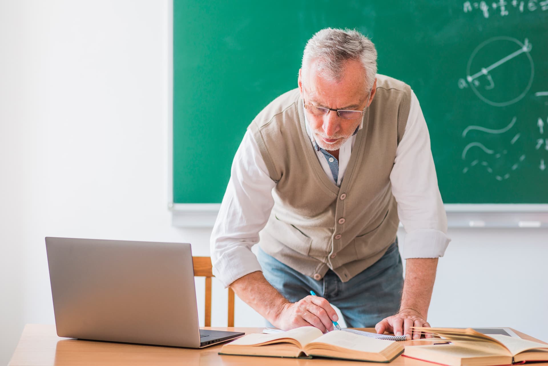 Profesor de matemáticas mayor escribiendo en una pizarra