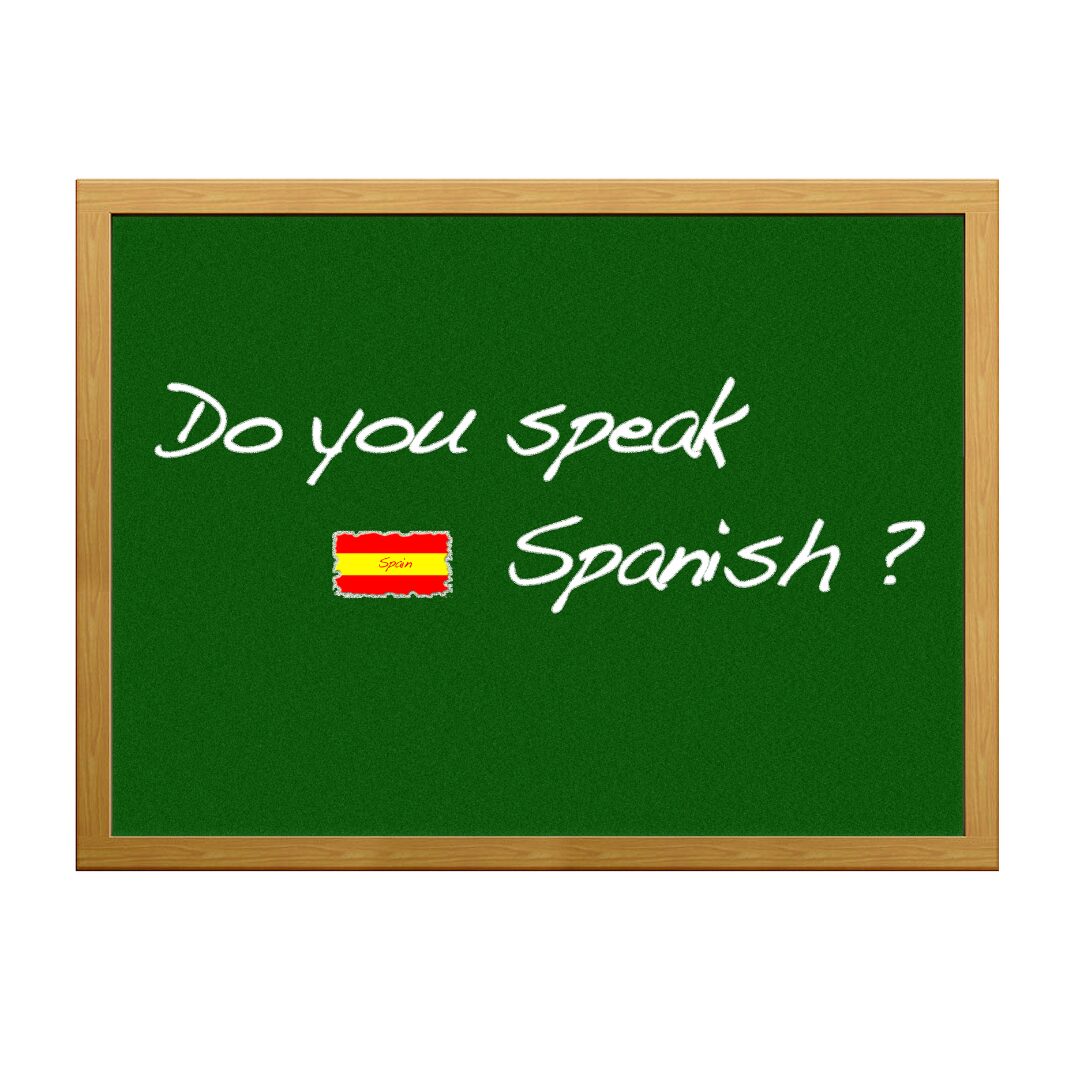 Pizarra verde con el texto 'Do you speak Spanish?' acompañado de una pequeña bandera de España