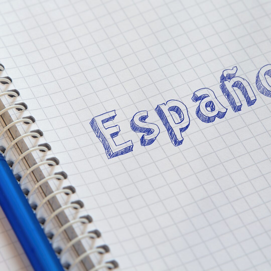 La palabra 'Español' escrita a mano en un cuaderno de cuadrícula, resaltando el aprendizaje del idioma español